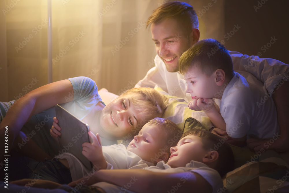 幸福的一家人在黑暗的房间里一起用平板电脑看电影