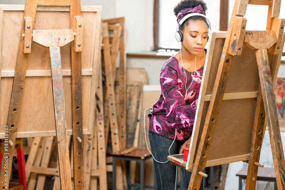 Young creative african ethnicity student drawing on the easel at the university studio