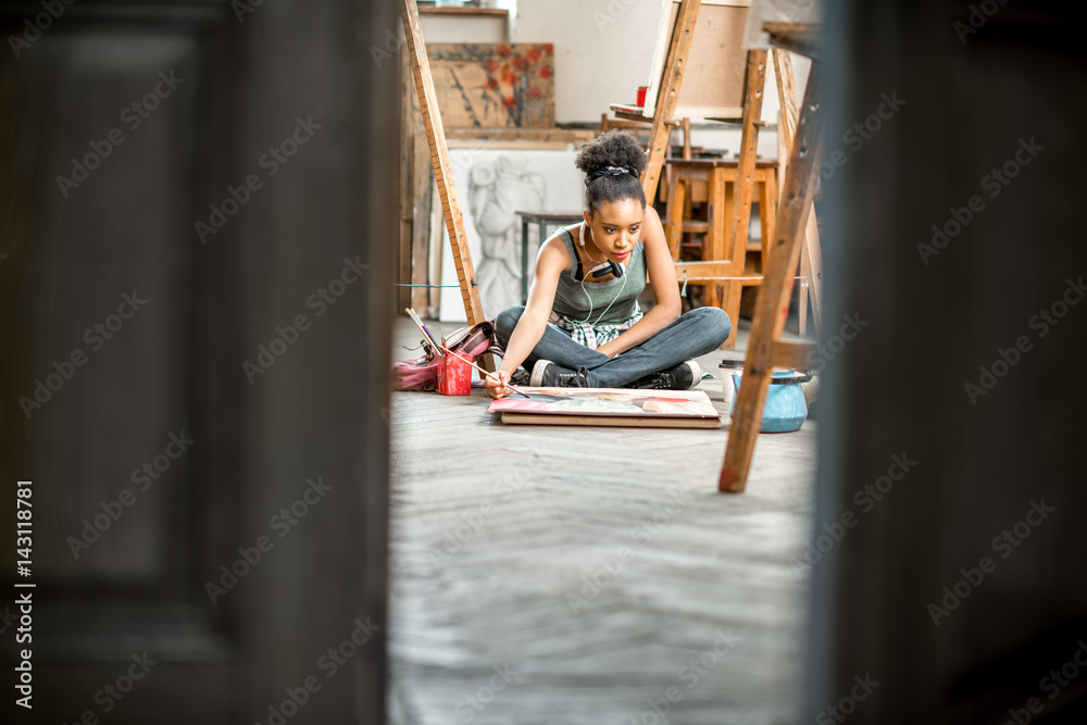 美丽的非洲裔学生在大学教室的地板上画画