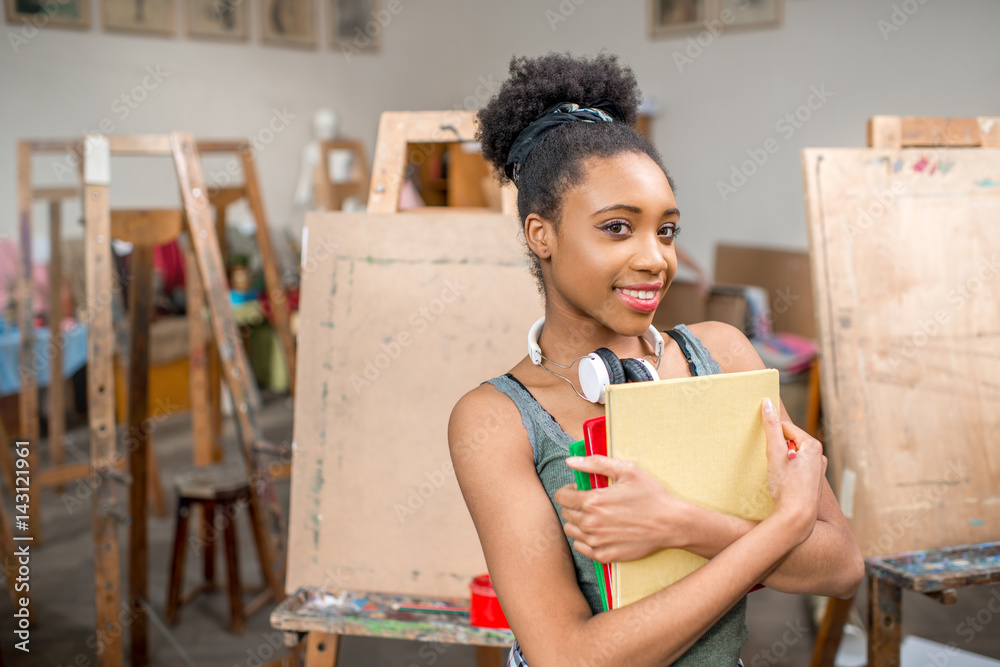 一位年轻的非洲裔学生在画室拿着书画画的肖像