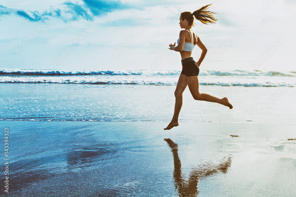活跃的运动型女性在泳池边沿着海浪奔跑，以保持健康。日落黑沙滩bea
