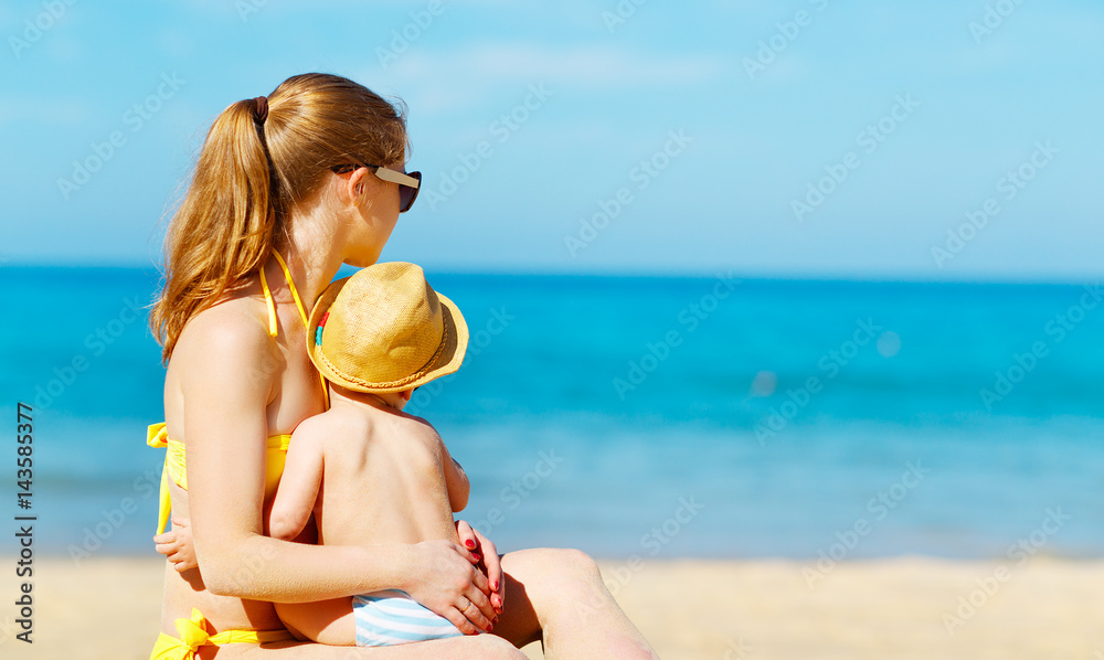 快乐的家庭母亲带着小儿子在夏天的海滩上