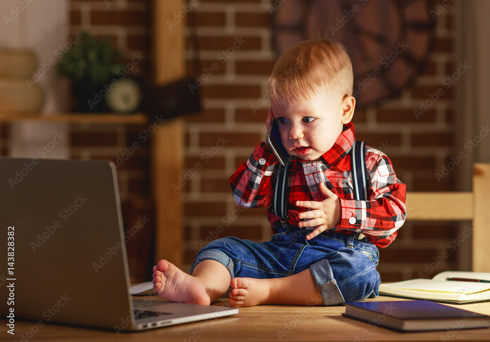 男婴在电脑上工作和打电话的概念