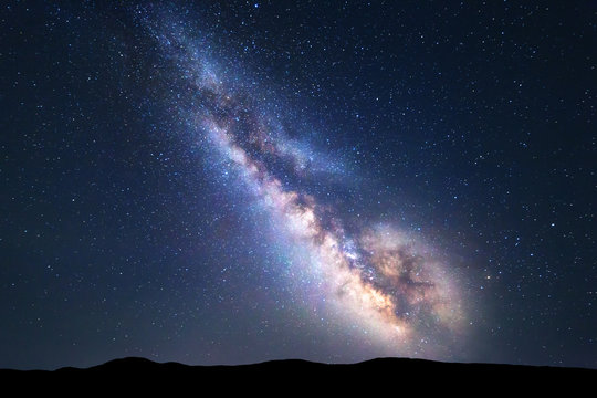 银河系。明亮的银河系、星空和夏季的山丘构成的彩色夜景。太空之旅
