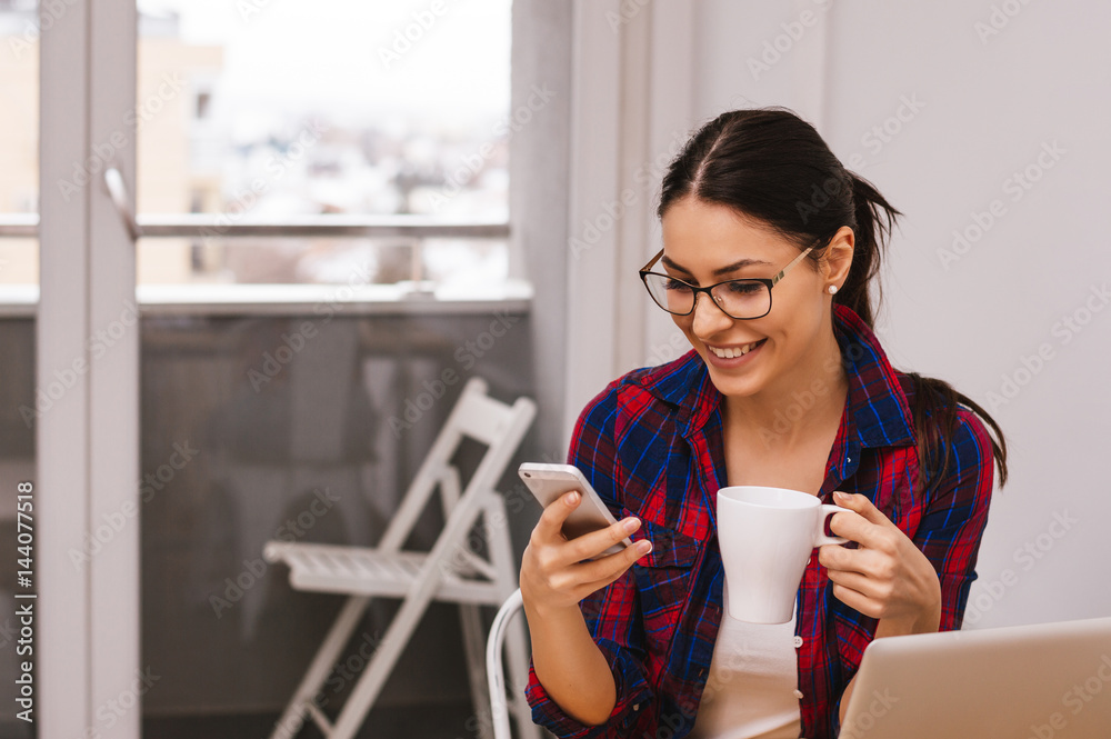 一位女商人通过手机查看电子邮件，并在室内拿着咖啡杯