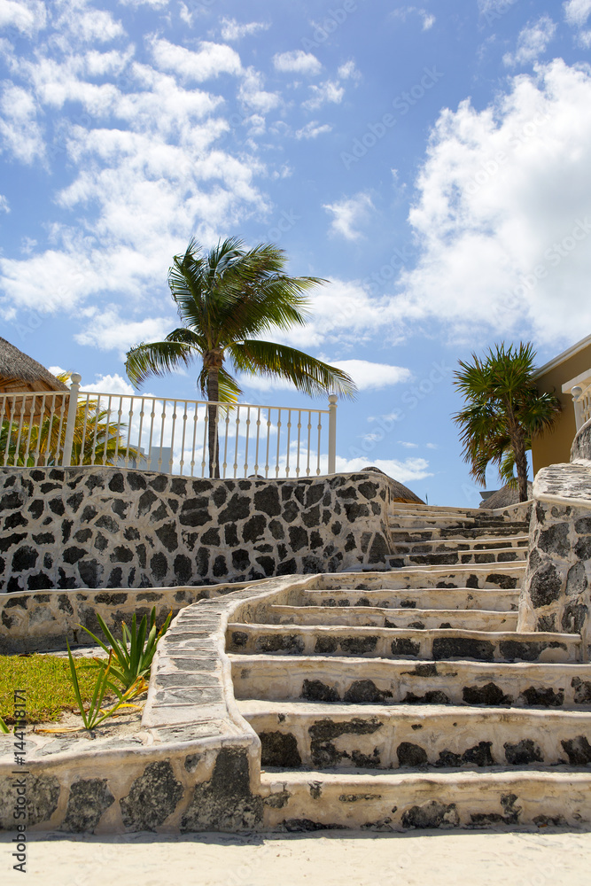 Stairs to the luxury resort on the beach. Palm trees and blue sky. White sand beach. Shore of the Ca