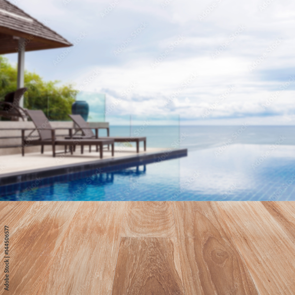 户外模糊沙滩椅上的木桌面，带游泳池和安达曼海景。