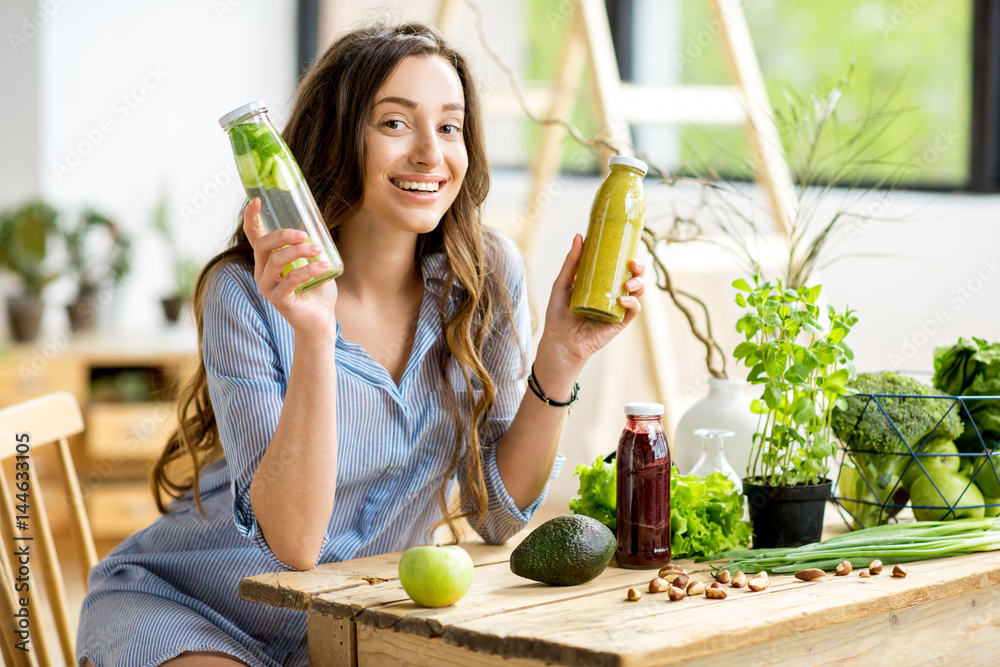 美丽的女人坐在家里享用健康的绿色食品和饮料。素食和排毒概念