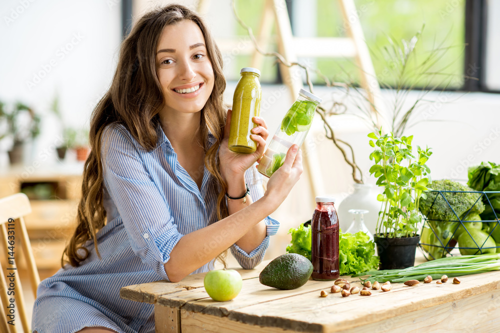 美丽快乐的女人，在家里享用健康的绿色食品和饮料。素食和排毒精华