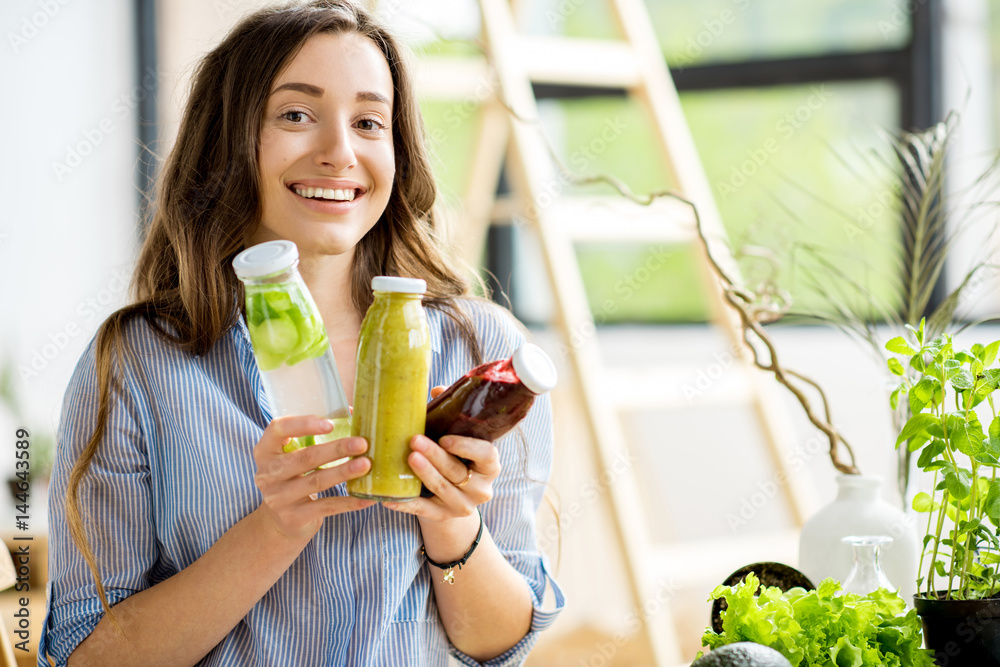 Beautiful happy woman sitting with drinks and healthy green food at home. Vegan meal and detox conce