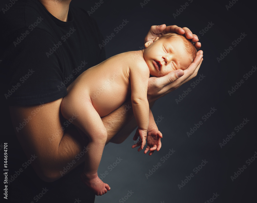  Newborn baby in his fathers hands in dark