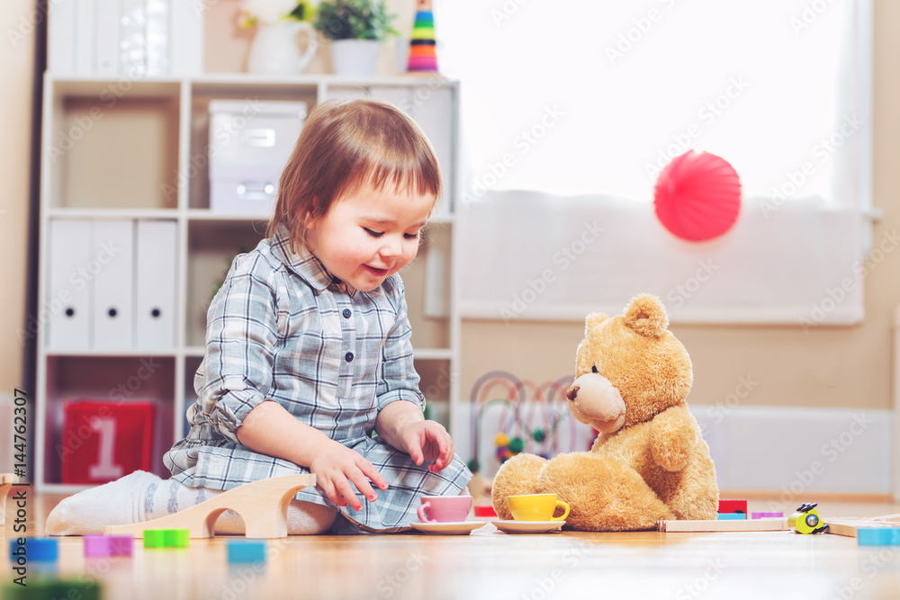 快乐的蹒跚学步的女孩在玩她的泰迪熊