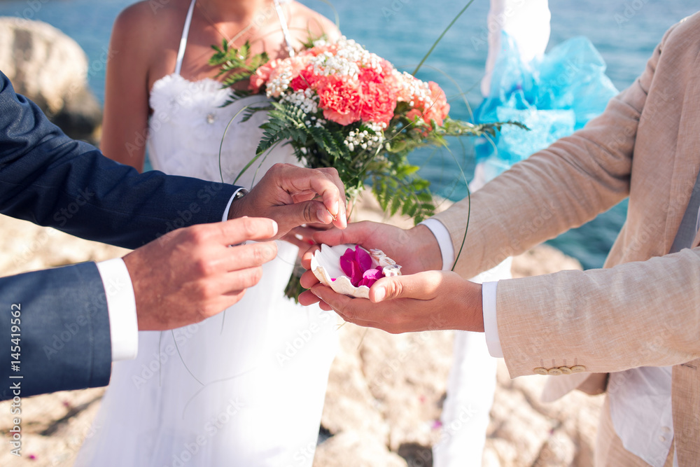 新郎接过戒指。塞浦路斯的婚礼，新娘和新郎在Agia Napa的石桥上。拱门