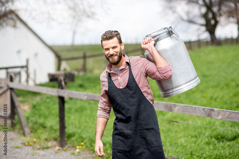 Portrait of a handsome milkman in apron walking with milk container outdoors on the rural scene back