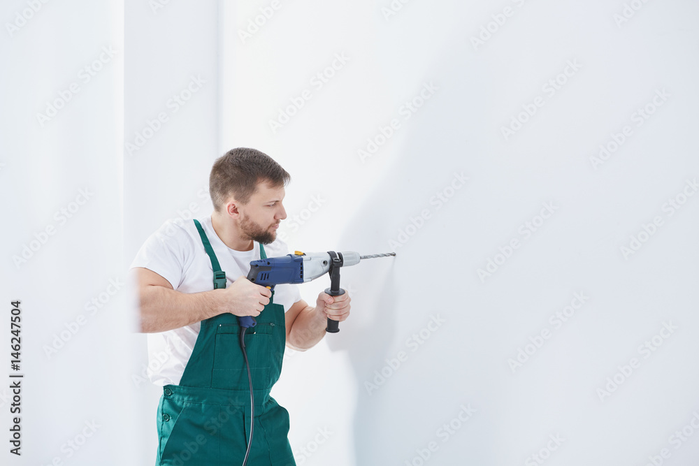 Worker drilling in a wall