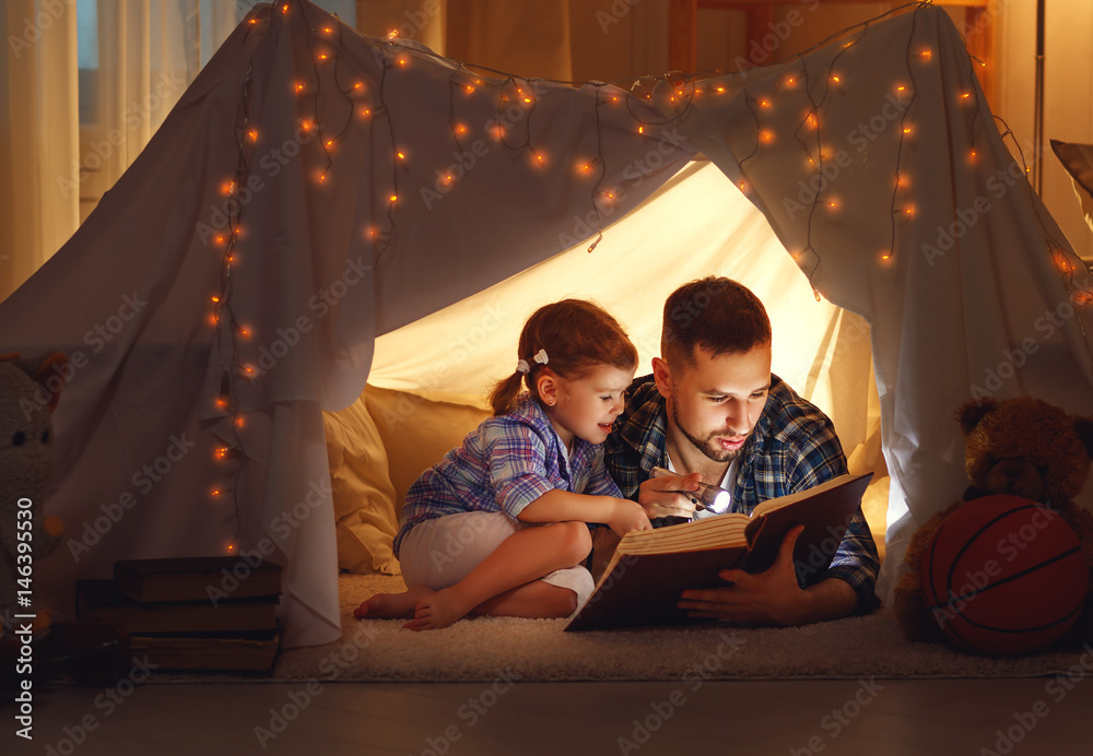 幸福的家庭父亲和孩子女儿在家里的帐篷里看书。