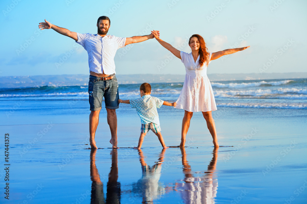 幸福的家庭-父亲、母亲、宝贝儿子手牵着手，在日落时一起在水池边散步和跳跃b