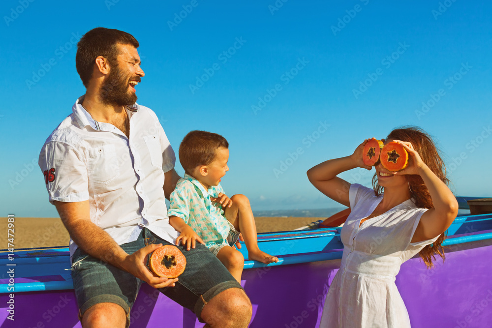 快乐有趣的家庭-父亲、母亲、小儿子一起在海边沙滩散步。人们野餐-