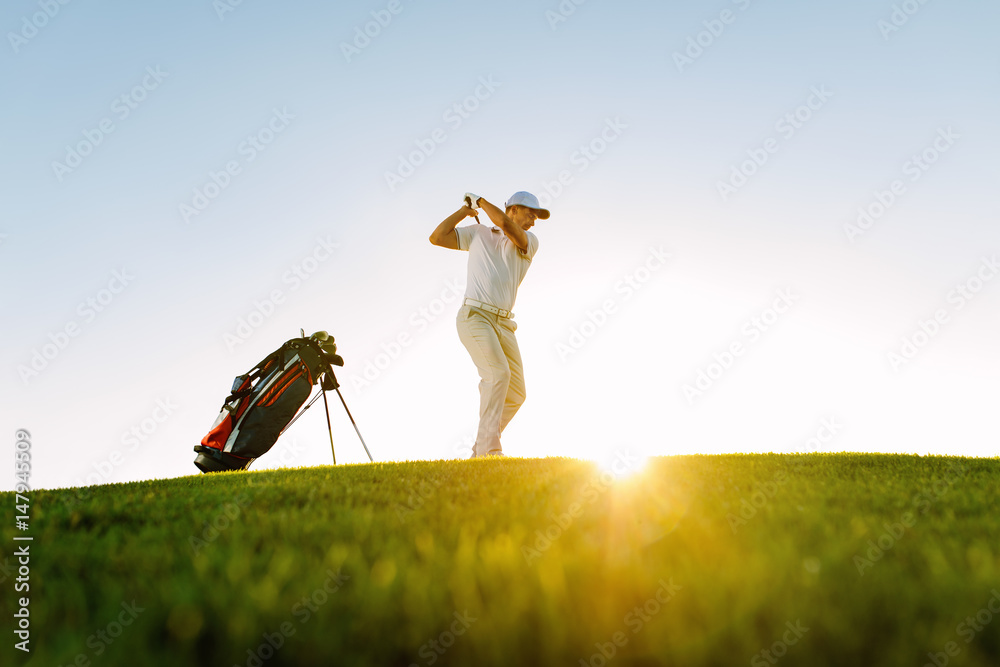 Male golfer taking shot on golf course