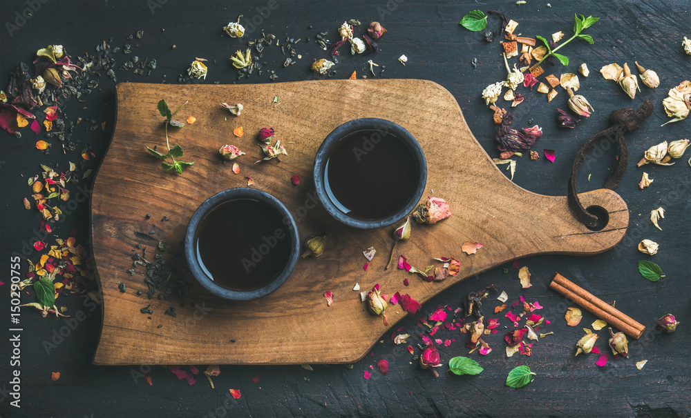 中国红茶，装在黑色石墙中，杯子放在黑色木质背景上的服务木板上