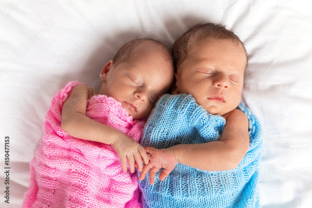 Newborn twins sleeping on bed together