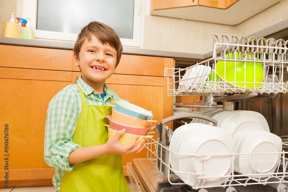 微笑的男孩从洗碗机里拿出碗