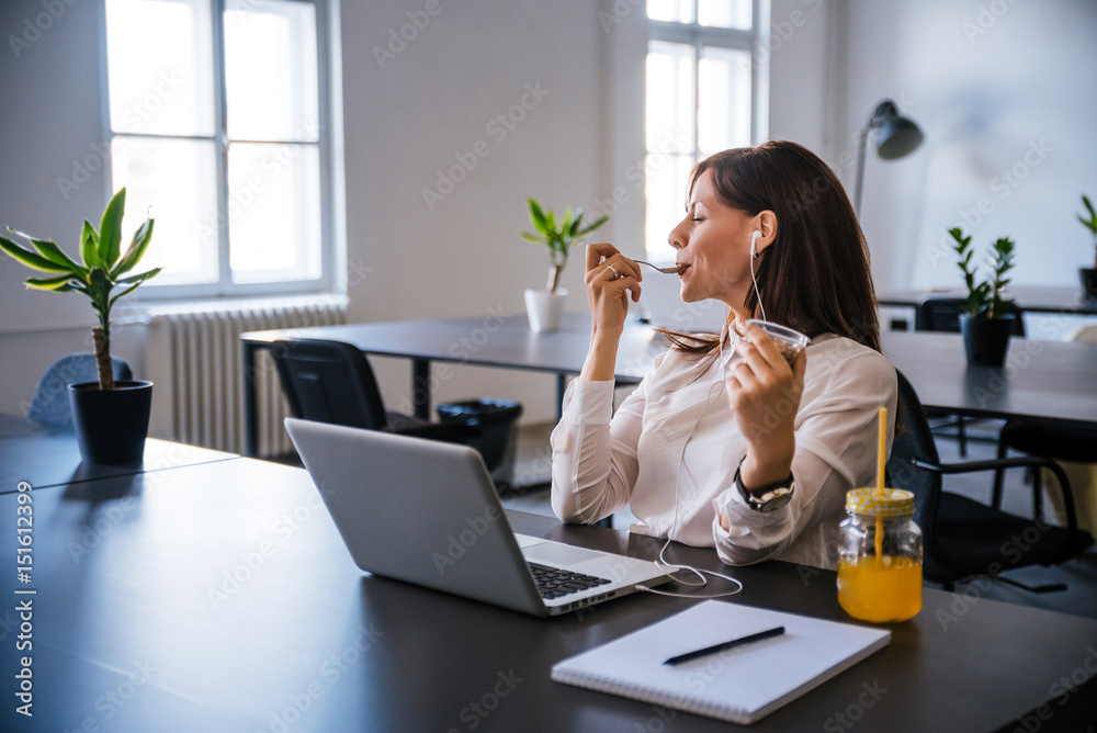Woman relaxing after work, eating ice cream and listening to music