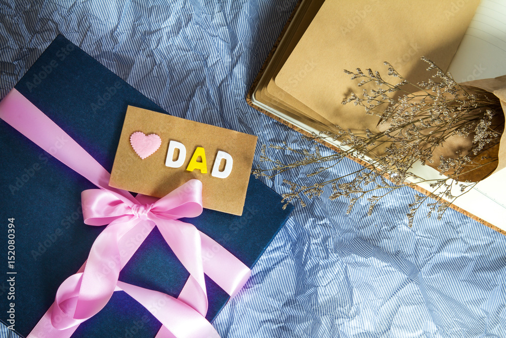 深蓝色礼盒，粉色缎带装饰，波蓝纸上写着爱爸爸的信息，快乐