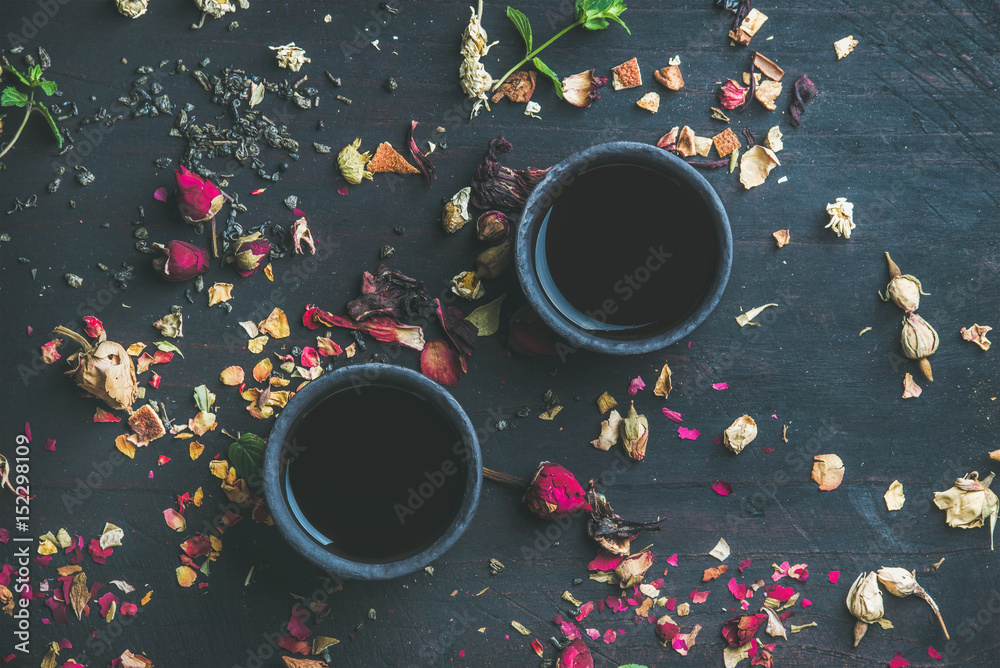 中国红茶，装在黑色石墙杯子里，黑色木质背景，配香草、花蕾、茶