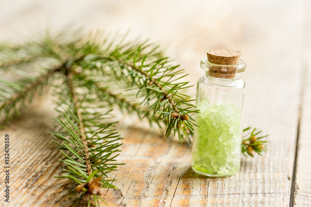 cosmetic spruce salt in bottles with fur branches on wooden table background