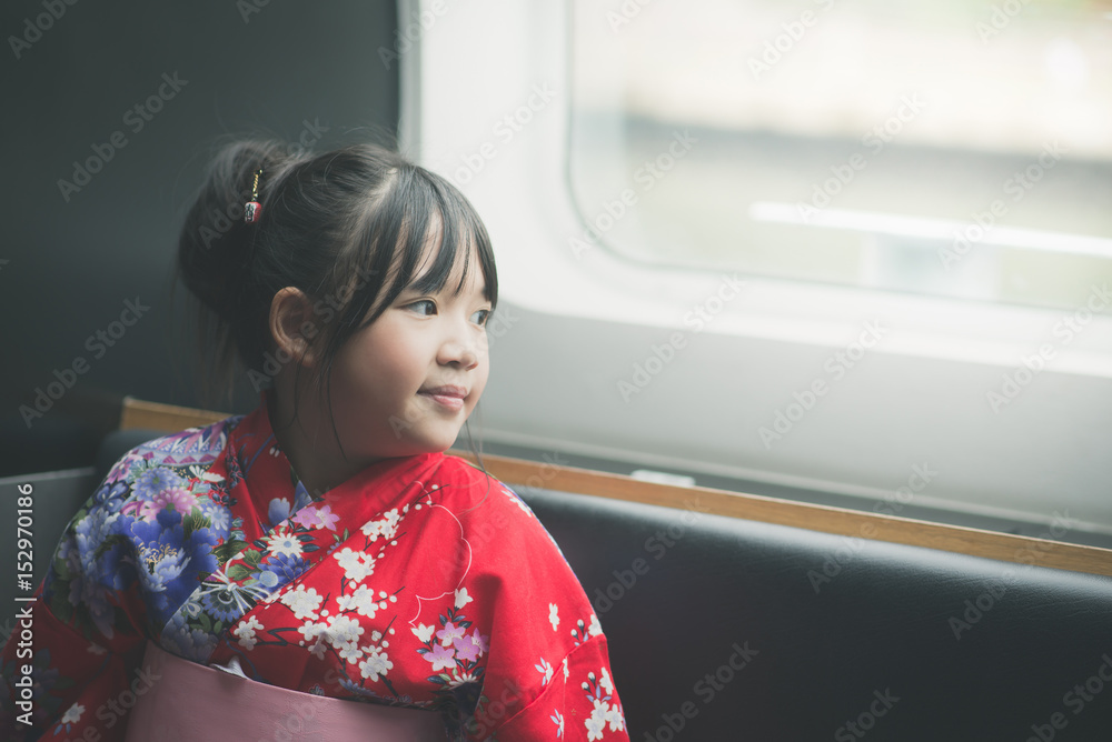 亚洲小女孩透过窗户看。她坐火车旅行，复古滤镜
