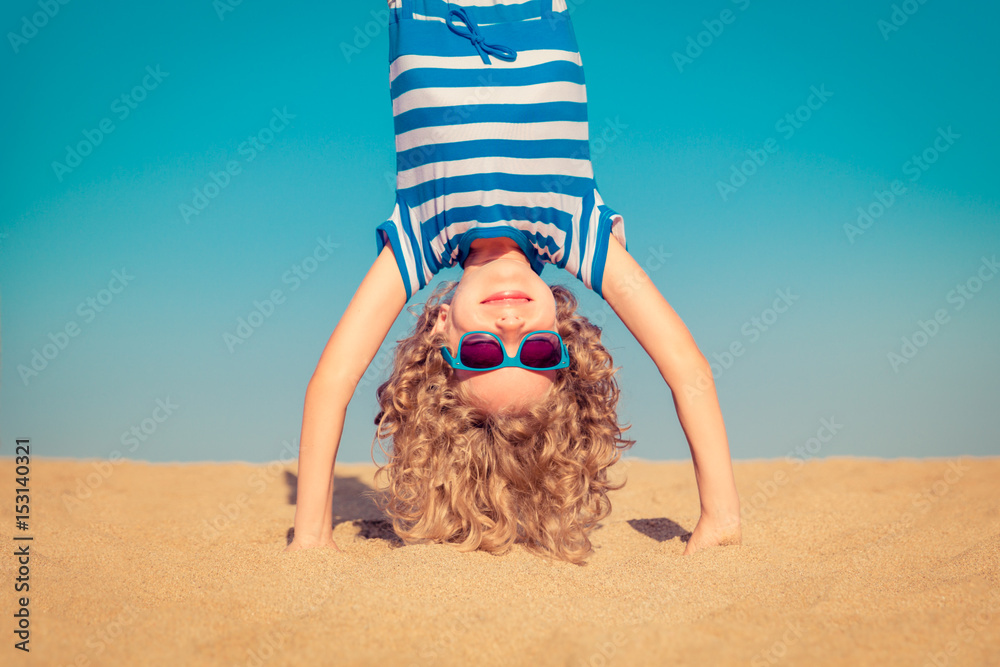 有趣的孩子倒立在沙滩上