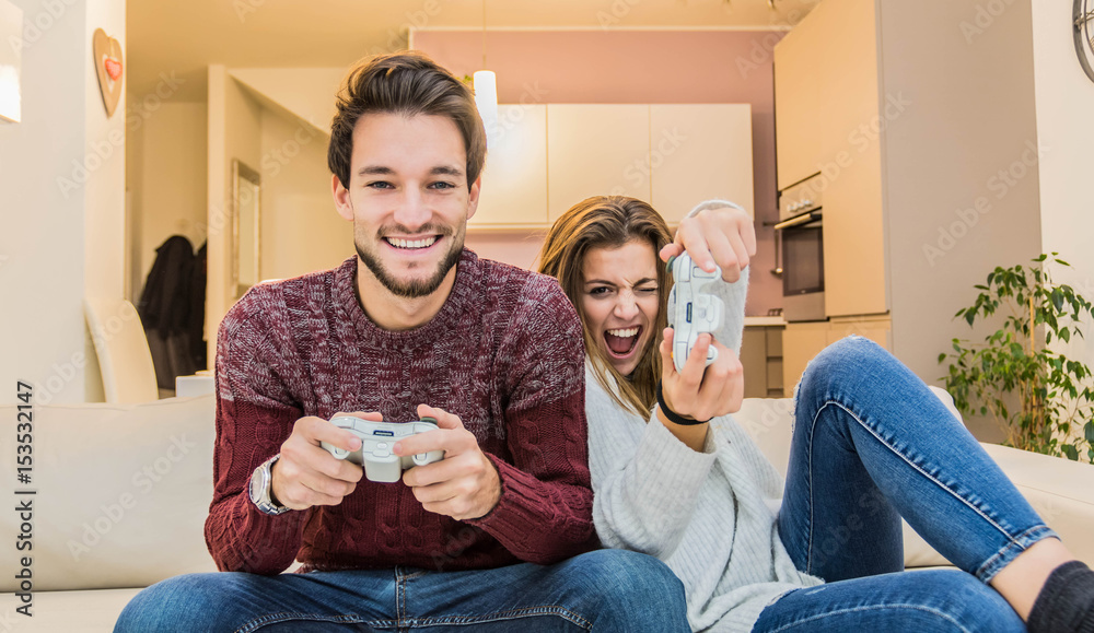 快乐的年轻夫妇在家玩电子游戏玩得很开心。