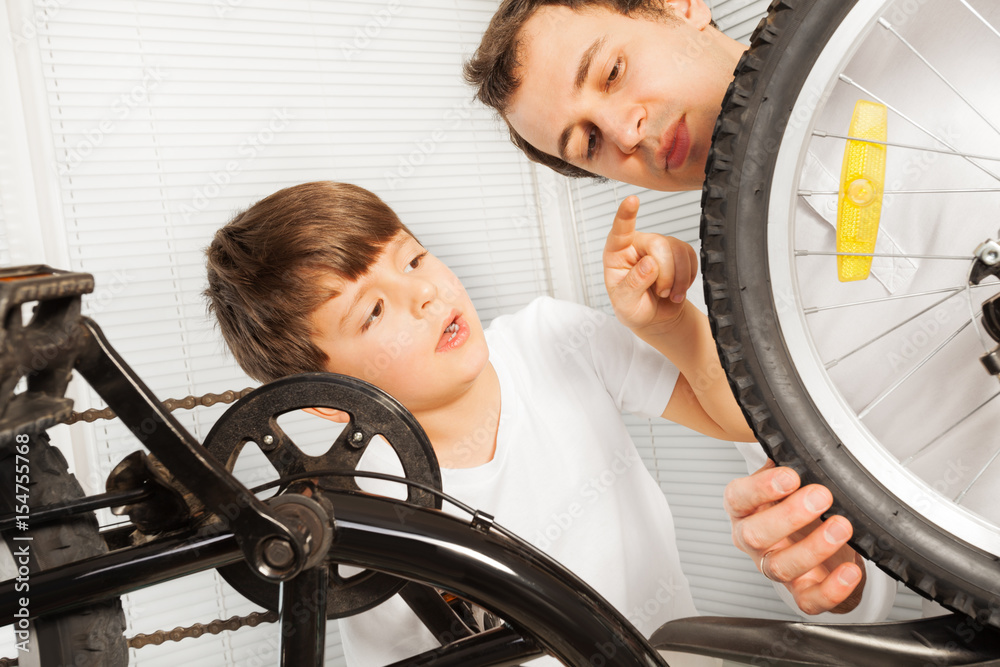 男孩和父亲一起检查自行车的轮子