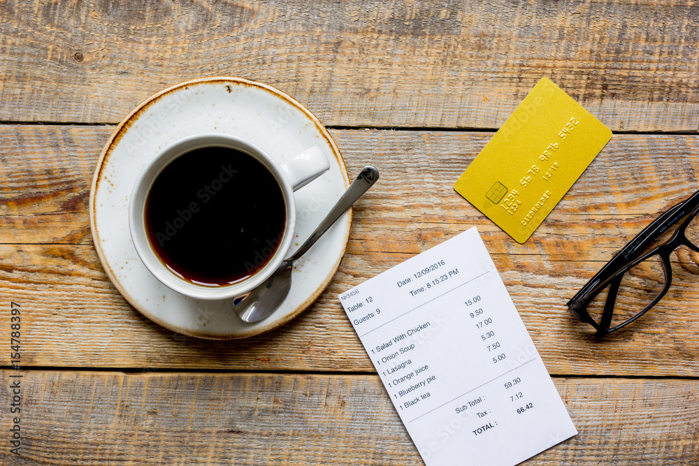 coffee and receipt bill for payment by credit card on wooden table background top view