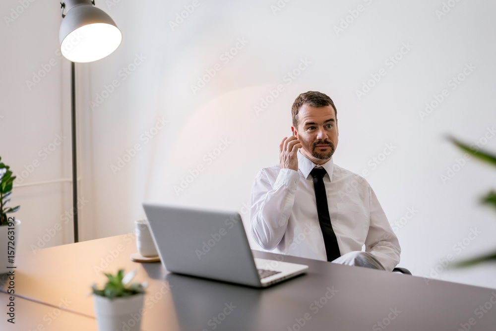 一名高级财务经理坐在办公室里处理新项目时打电话的镜头