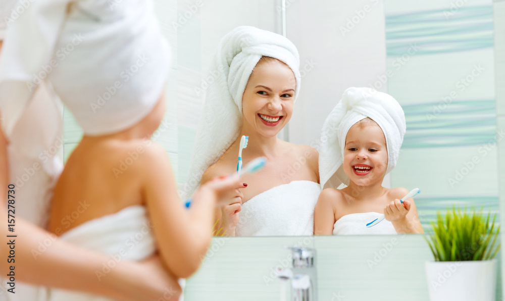 Mother and child daughter brush their teeth with  toothbrush.