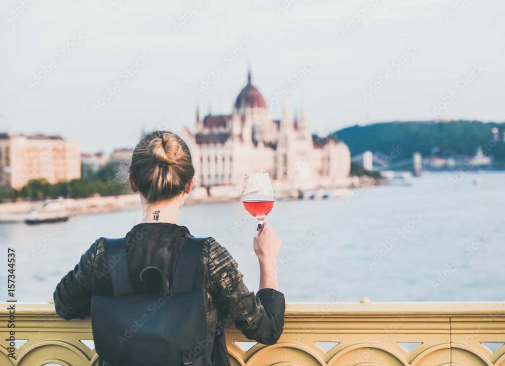 Young woman tourist standing with glass of rose wine at Margaret bridge in Budapest, Hungarian Parli