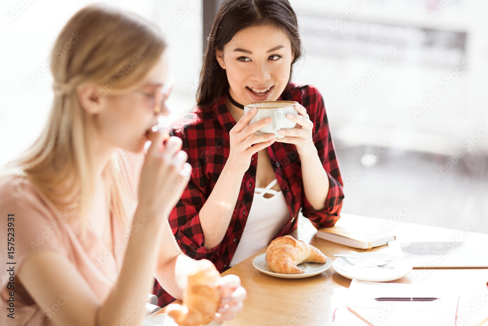 年轻女孩在咖啡馆吃羊角面包喝咖啡，咖啡休息