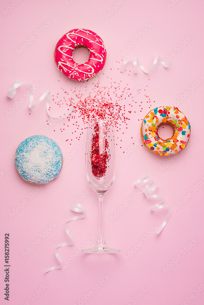 庆祝活动平淡无奇。香槟酒杯上有五颜六色的派对彩带和粉红色的美味甜甜圈