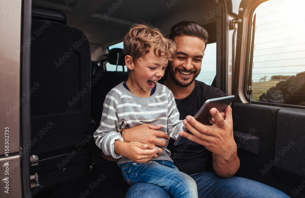 快乐的父子使用数字平板电脑进行公路旅行