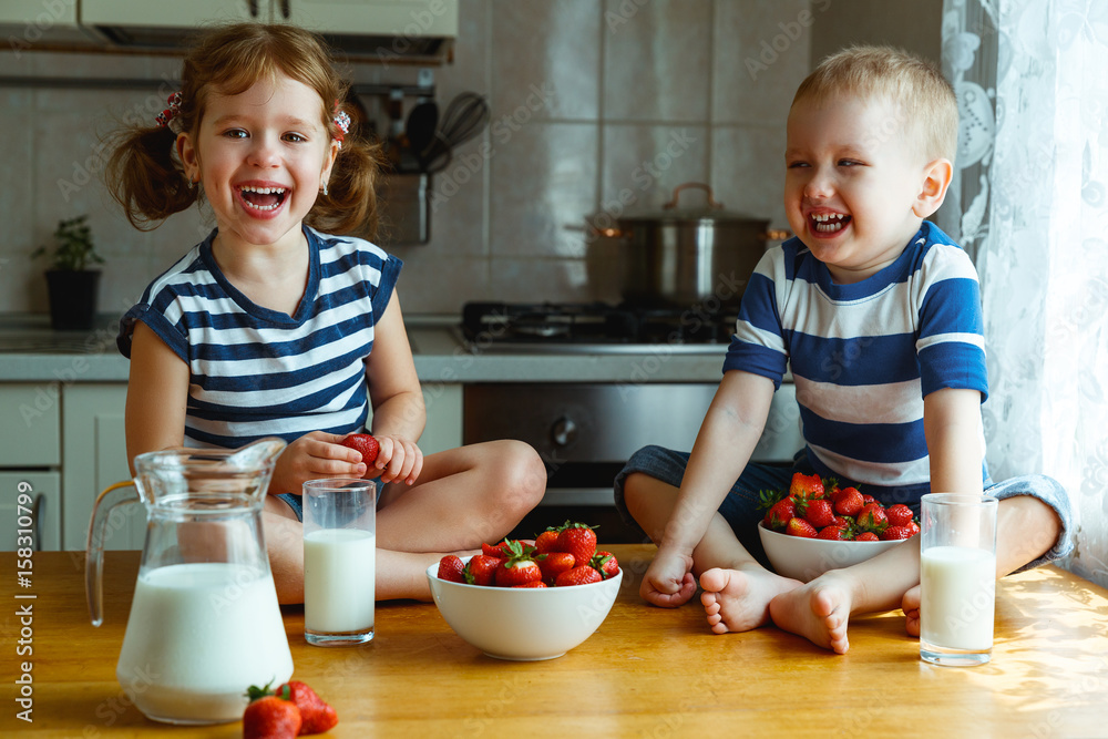快乐的孩子兄弟姐妹一起吃草莓配牛奶