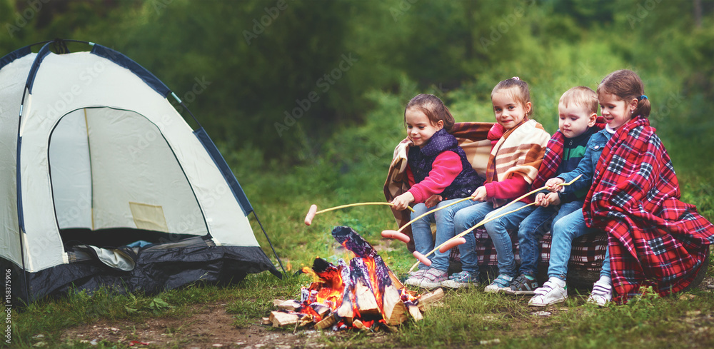 孩子们在帐篷附近的木桩上笑着炸香肠。
