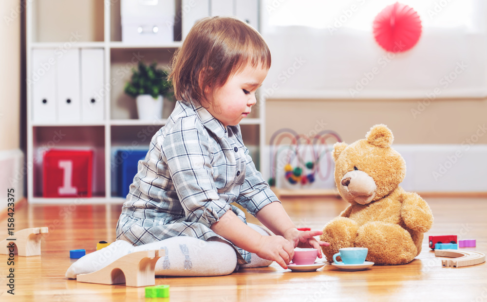 Happy toddler girl playing with her teddy bear