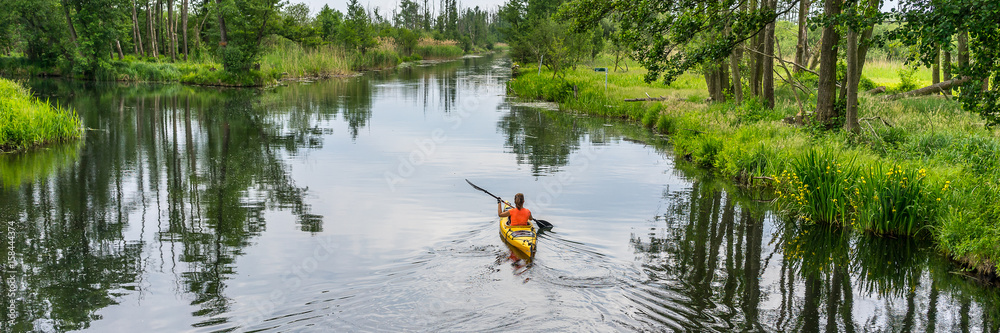 一个女孩在河上划皮划艇的全景，美丽的自然景观