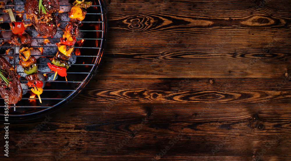 木地板上烤架上鲜肉和蔬菜的俯视图。烧烤、烤架和食物浓缩