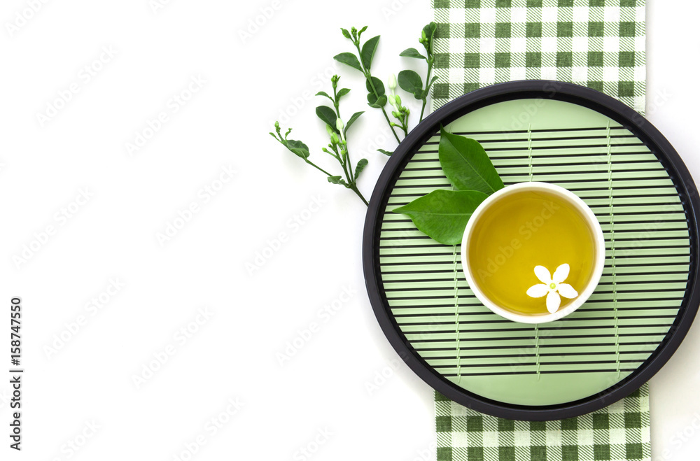 一杯热茶的俯视图，带有绿叶装饰，白底绿色餐巾