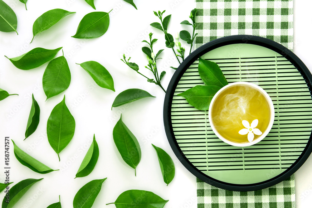 一杯热茶的俯视图，带有绿叶装饰，白底是绿色餐巾