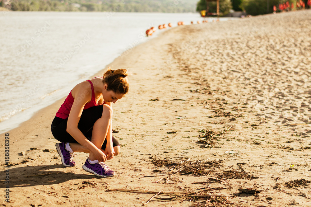 女性系上运动鞋，为夏天在海滩跑步和锻炼做好准备