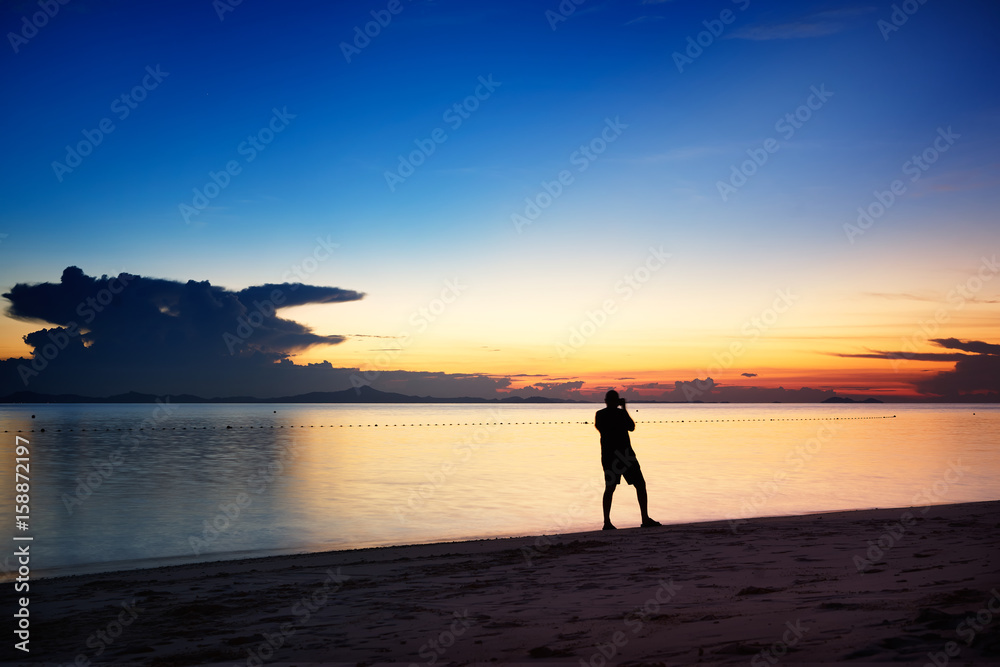 旅行者在马来西亚拉瓦岛的海滩上拍摄令人惊叹的日落。
